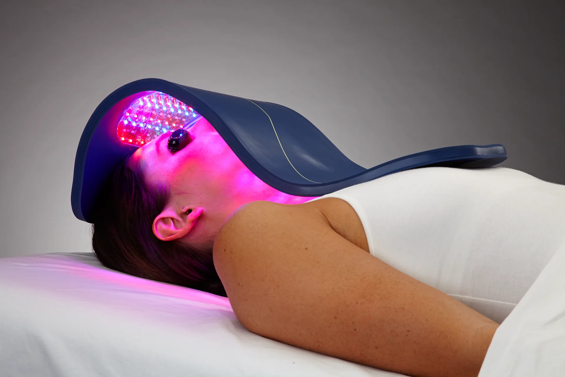 Red LED light therapy panel positioned over a face for anti-aging treatment in a spa setting